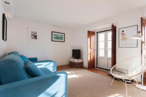 a living room with a blue couch and a tv at FLH Bairro Alto Loft with Sunny Terrace in Lisbon