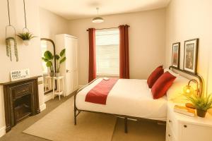 a bedroom with a bed with red pillows and a fireplace at Liverpool Escape - 5 min walk to LFC Stadium, Sleeps 8, free parking, newly renovated home in Liverpool