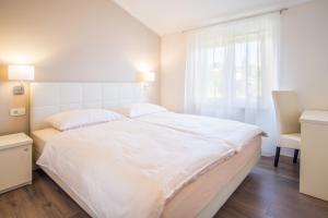a white bedroom with a large bed and a chair at ValDeSara in Malinska