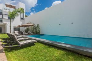 a swimming pool with chaise lounge chairs next to a house at Malibu Residential 3BD - Or in Cozumel
