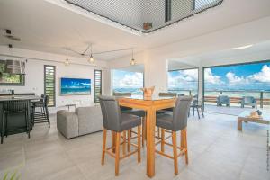 a dining room and living room with a table and chairs at Villa de luxe vue exceptionnelle - MQDI92 10p in Le Diamant