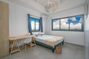 a bedroom with a bed and a desk and windows at Villa de luxe vue exceptionnelle - MQDI92 10p in Le Diamant