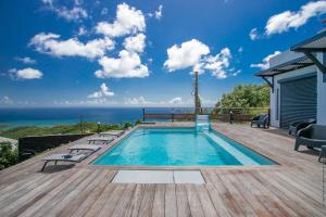 a swimming pool on a deck with the ocean in the background at Villa de luxe vue exceptionnelle - MQDI92 10p in Le Diamant