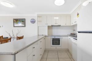 a white kitchen with white cabinets and appliances at Bellardoo Holiday Apartments in Mooloolaba