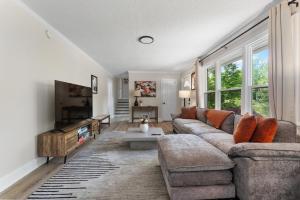 een woonkamer met een bank en een tv bij Luxury 4BR Pool Jacuzzi Arcade USC Ft Jackson in Columbia