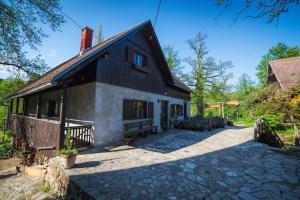 a black and white house with a stone driveway at Guesthouse Pod rastockim krovom in Slunj