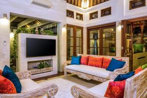 a living room with two couches and a tv at Villa Zamaya Sanur in Sanur