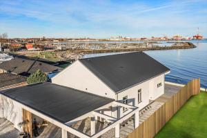 un bâtiment blanc avec un toit noir à côté de l'eau dans l'établissement TV1512-Frederikshavn-Saltebakken-50-A, à Frederikshavn