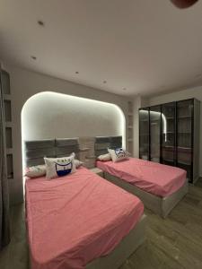 1 Schlafzimmer mit 2 Betten mit rosa Bettwäsche und einem Spiegel in der Unterkunft EMPIRE-K Homes -Khalid's Villa in New cairo
