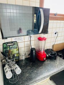a kitchen counter with a red blender on it at Apartamento Em frente a praia - Piscina condomínio América Praia, acesso privativo para a praia in Porto Seguro