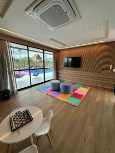 un salon avec une table, des chaises et une télévision dans l'établissement Flat no Paraíso da praia do Cupe - Porto de Galinhas, à Porto de Galinhas