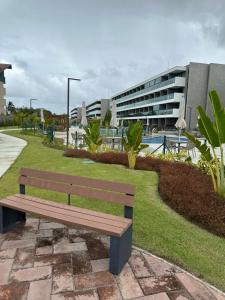 un banc en bois assis devant un bâtiment dans l'établissement Flat no Paraíso da praia do Cupe - Porto de Galinhas, à Porto de Galinhas