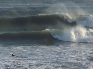 a person laying in the ocean with a large wave at Chapa Surfhaus in Colonia Chapadmalal