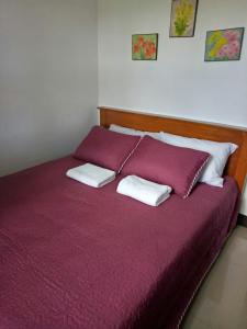 a red bed with two white pillows on it at Framelyn's Suites in Breezy Tagaytay in Tagaytay