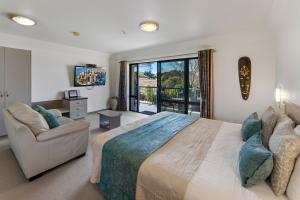 a bedroom with a bed and a couch and a balcony at Avalon Manor Motel in Motueka