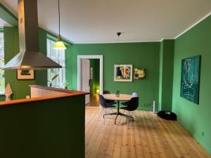 a kitchen with green walls and a table and chairs at GreenBrook Homes in Aalborg