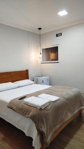 a bedroom with a large bed with towels on it at Flats & Suítes do Lago in Guapé