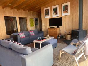 a living room with blue couches and a tv at Casa orilla playa en Chiloé in Aytuy
