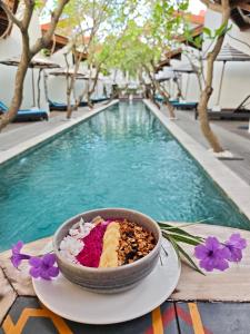 eine Schüssel mit Essen auf einem Teller neben einem Swimmingpool in der Unterkunft Jali Resort - Gili Trawangan in Gili Trawangan