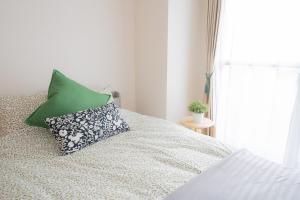 a bedroom with a bed with a green pillow at SN2A おしゃれで広々としたお部屋 大須商店街徒歩10分 8人可能 Stylish and spacious room 10-minute walk to Osu Shopping Street Accommodates 8 people in Nagoya