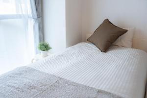 a white bed with a pillow and a window at SN2A おしゃれで広々としたお部屋 大須商店街徒歩10分 8人可能 Stylish and spacious room 10-minute walk to Osu Shopping Street Accommodates 8 people in Nagoya +14 photos