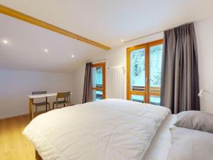 a bedroom with a large white bed and a desk at Apartment in Les Agettes with ski storage in Agettes