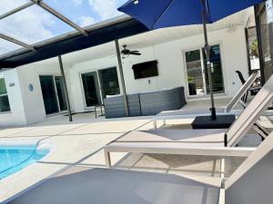 a patio with a table and an umbrella next to a pool at Stylish Home near Anna Maria Island Beaches - Heated Pool - Oasis in Bradenton