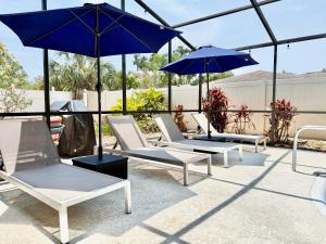 a group of chairs and umbrellas on a patio at Stylish Home near Anna Maria Island Beaches - Heated Pool - Oasis in Bradenton