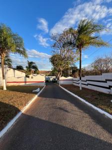 an empty road with palm trees and a fence at Park Motel in Pará de Minas