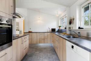 a large kitchen with wooden cabinets and a sink at TV1295-Bindslev-Uglevej-6 in Bindslev +21 photos