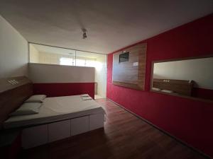 a room with a bed and a red wall at Park Motel in Pará de Minas