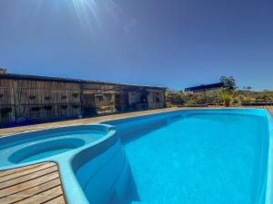 a blue swimming pool with a wooden bench next to it at Casa Borba Chalé Rústico in Alto Paraíso de Goiás