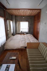 Un dormitorio con una cama grande y un sofá. en めくる, en Matsumoto