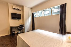 a bedroom with a bed and a window and a chair at San Diego Suites Pampulha - Flats Particular in Belo Horizonte