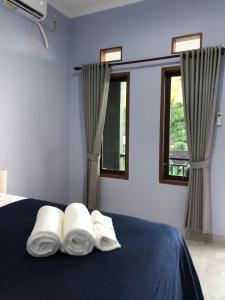 a bedroom with three towels on a bed with two windows at Naomi Homestay in Padangbai