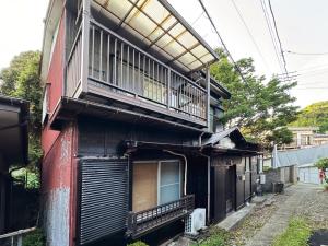 a building with a balcony on the side of it at 横須賀 鴨 古民家の宿 -自然と安らぎの里 in Yokosuka
