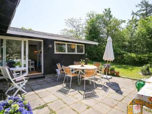 a patio with a table and chairs and an umbrella at 6 person holiday home in Tisvildeleje