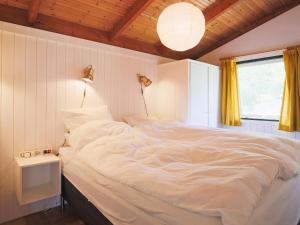 a large white bed in a room with a window at 6 person holiday home in Tisvildeleje