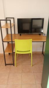 a yellow chair in front of a desk with a television at Le condo douillet d'Avignon in Avignon