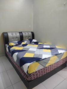 a bed with a black frame and a colorful comforter at Stingless Bee Homestay in Kluang