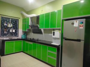 a green kitchen with green cabinets and a refrigerator at Stingless Bee Homestay in Kluang