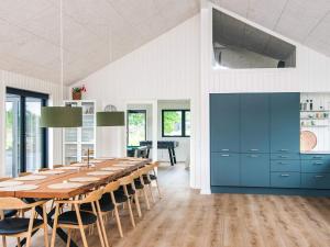 a large dining room with a long table and blue cabinets at 5 star holiday home in Ansager in Ansager
