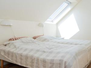 a white bed in a white room with a window at 6 person holiday home in Ringkøbing in Ringkøbing