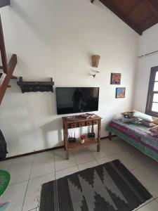 a living room with a tv and a table at Casa Pouso dos Colibris em Paraty in Paraty