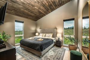 a bedroom with a bed and large windows at Luxury Log Home with a Hot Tub in Selfoss