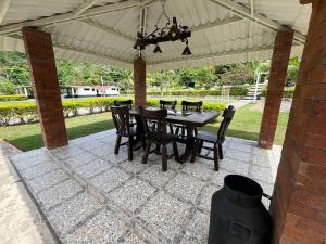 a patio with a table and chairs under a roof at Casa Quinta Arbelaez in Arbeláez