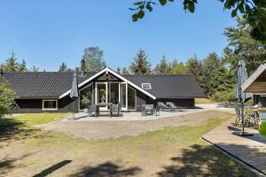 ein schwarzes Haus mit einer Terrasse und einem Haus in der Unterkunft TV1661 Jerup - Blåbærvej 5 in Jerup