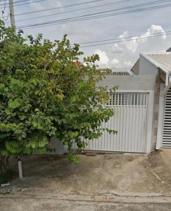 a house with a white gate and a tree at Shekinah in Sumaré