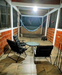 un patio con sillas, una mesa y una hamaca en Casita entre árboles, casa de huéspedes céntrica y cómoda en San Fernando, Cali, en Cali