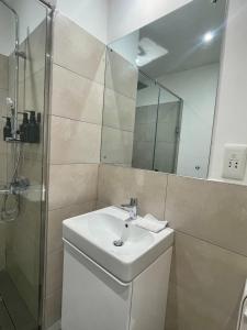 a bathroom with a sink and a shower with a mirror at Loxwood House Luxury Apartment in Accra